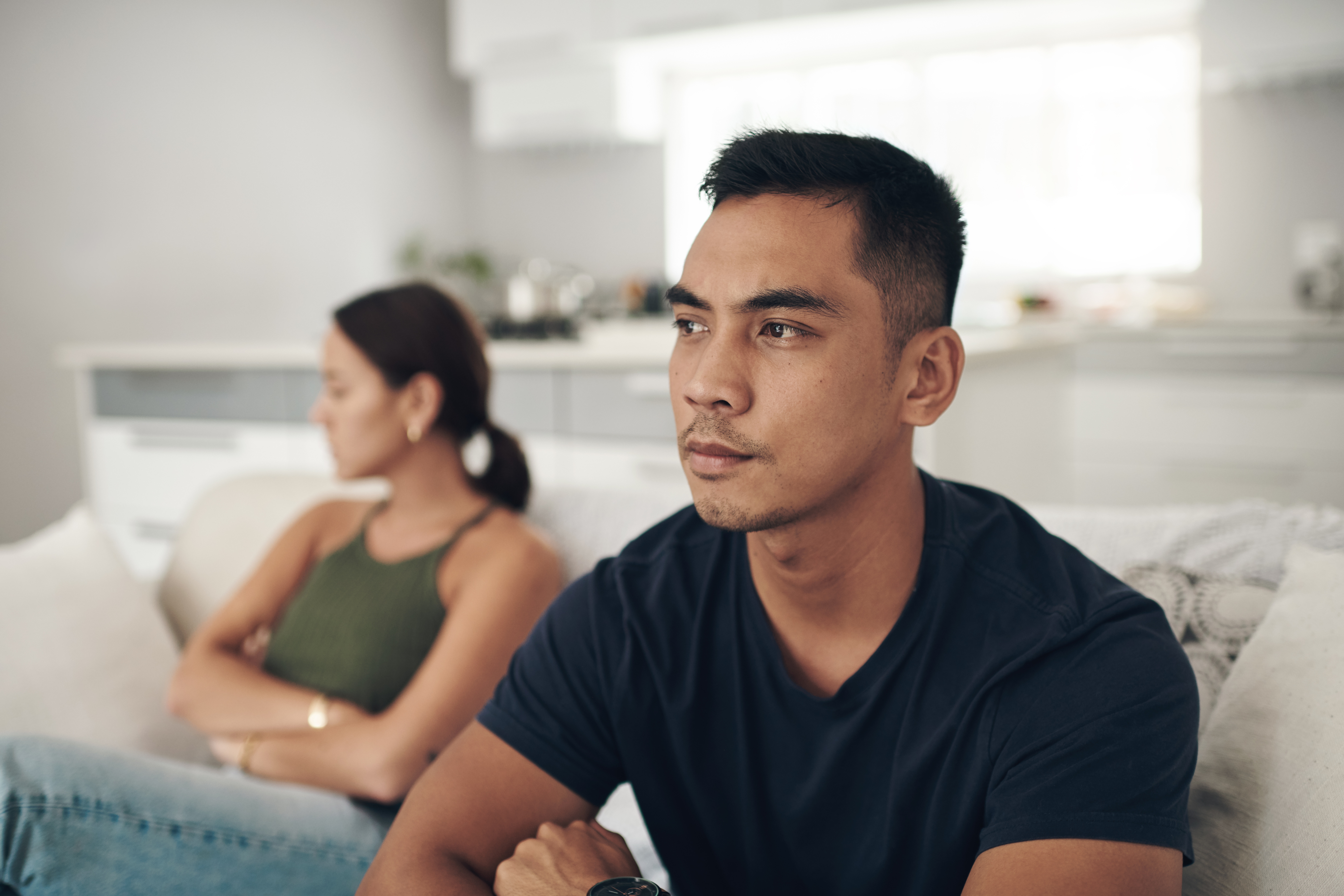 Pareja sentada en casa conversando con seriedad, representando una reconciliación después de una denuncia de violencia doméstica en Virginia.